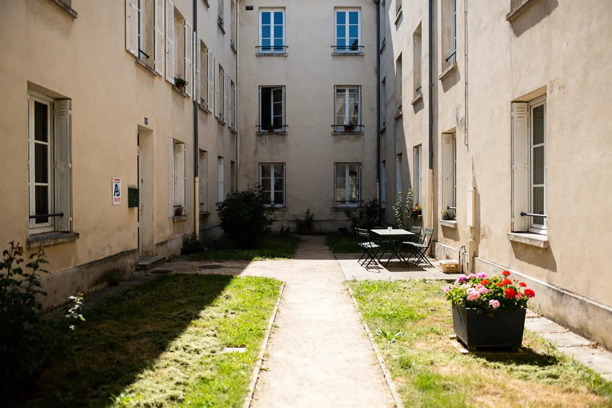 Cour commune avec tables chaises fleurs illustrant le droit et devoir des résidents