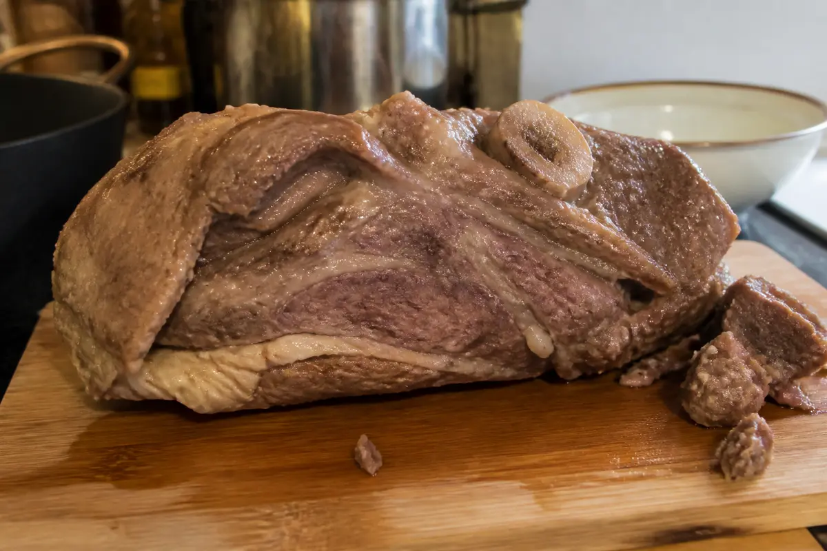 Un morceau de viande cuite sur planche en bois, dans une cuisine.